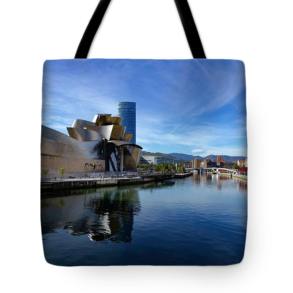 Spain Bilbao Guggenheim Museum Basque Country Frank Gehry Contemporary Architecture Nervion River City Daring And Innovative Curves Building Exterior Spectacular Building Deconstructivism Ferrovial Clad In Glass Tote Bag featuring the photograph Bilbao in autumn with blue skies next to the river Nervion by Andy Myatt