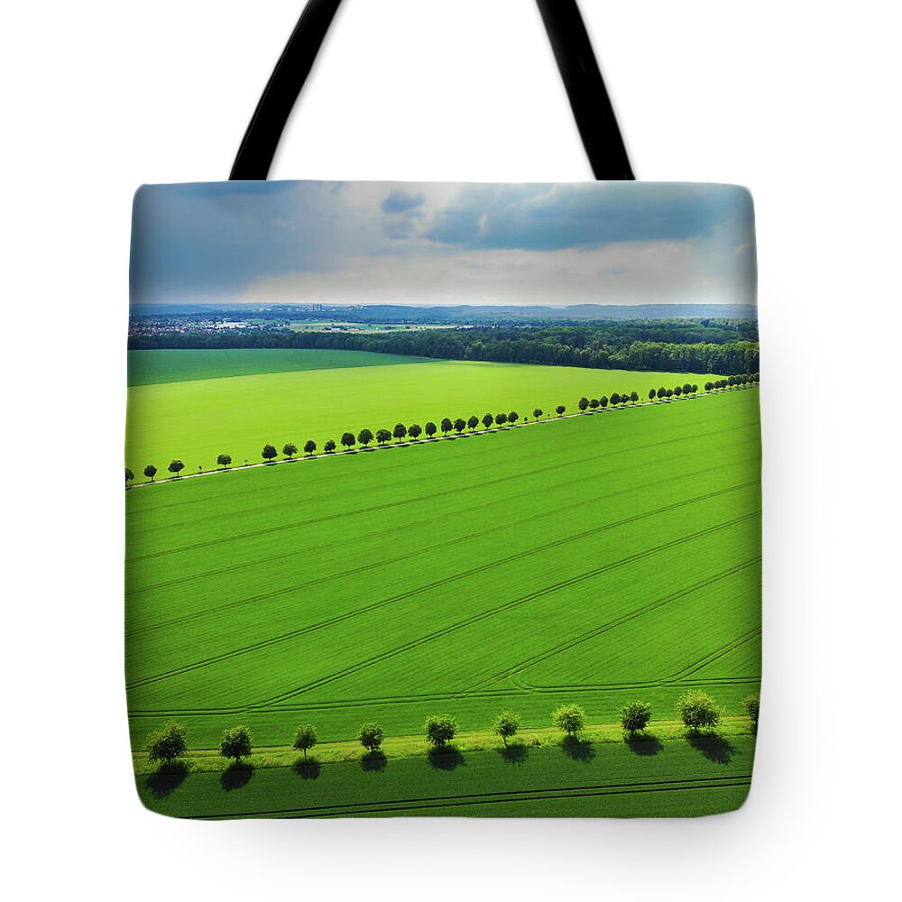 Green Tote Bag featuring the photograph Bright green landscape with fields and trees by Matthias Hauser