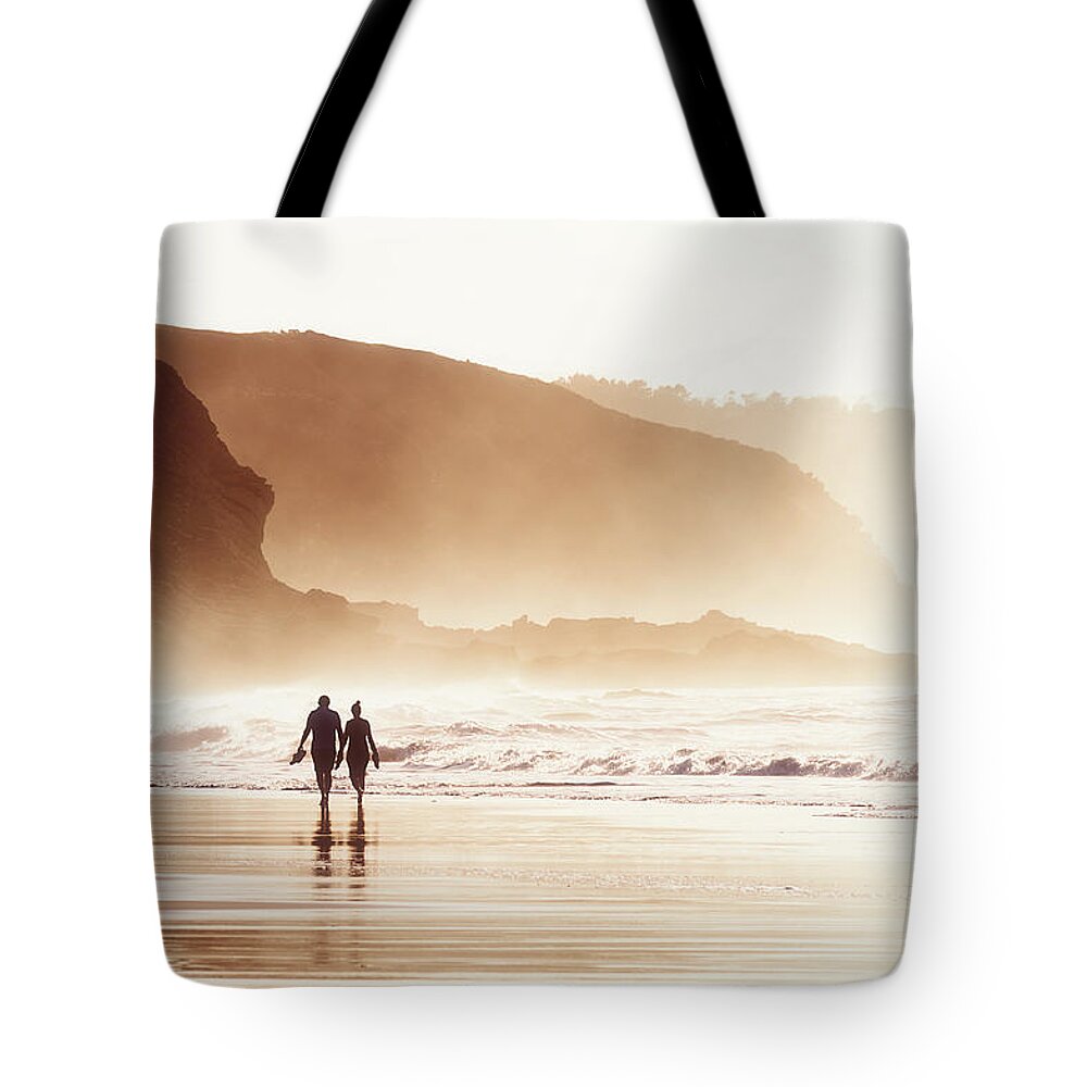 Couple Tote Bag featuring the photograph Couple Walking On Beach With Fog by Mikel Martinez de Osaba