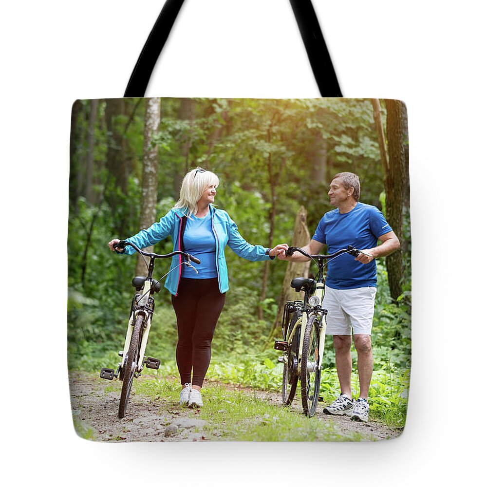 Man Tote Bag featuring the photograph Elderly marriage with bicycles holding hands by Michal Bednarek