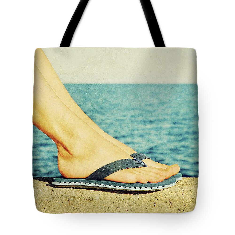 Foot Tote Bag featuring the photograph Female feet in blue flip-flops, retro image by GoodMood Art