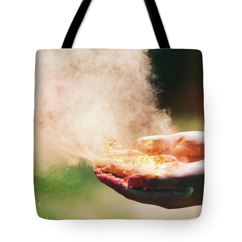 Hands Tote Bag featuring the photograph Holi powder held in woman's hand and a cloud of dust by Michal Bednarek