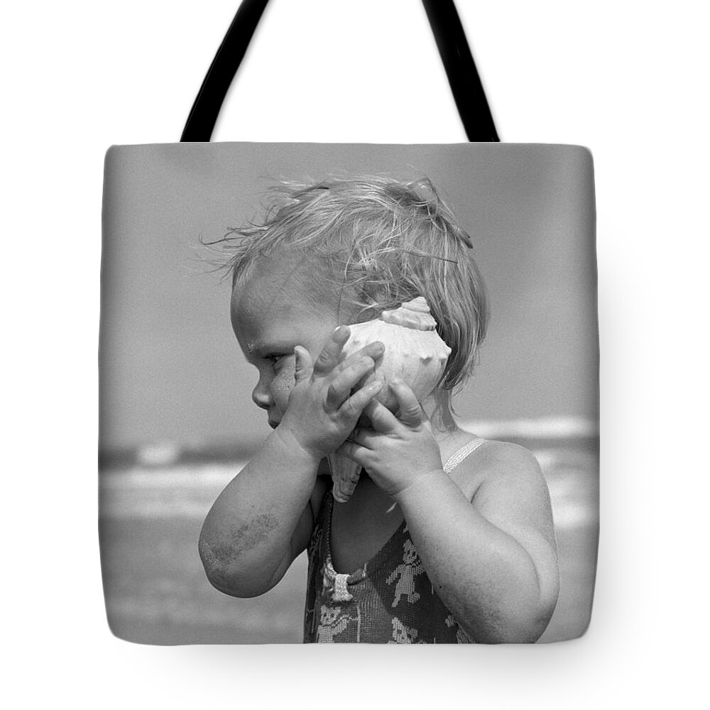 1950s Tote Bag featuring the photograph Little Girl Listening To Seashell by H Armstrong Roberts and ClassicStock