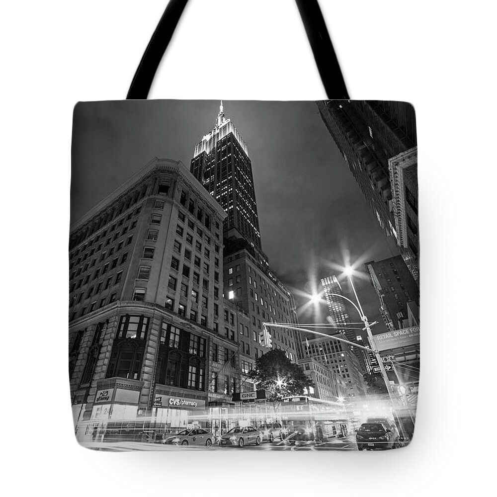 New.york Tote Bag featuring the photograph Looking up at the Empire State building from Fifth Avenue at night New York NY Black and White by Toby McGuire