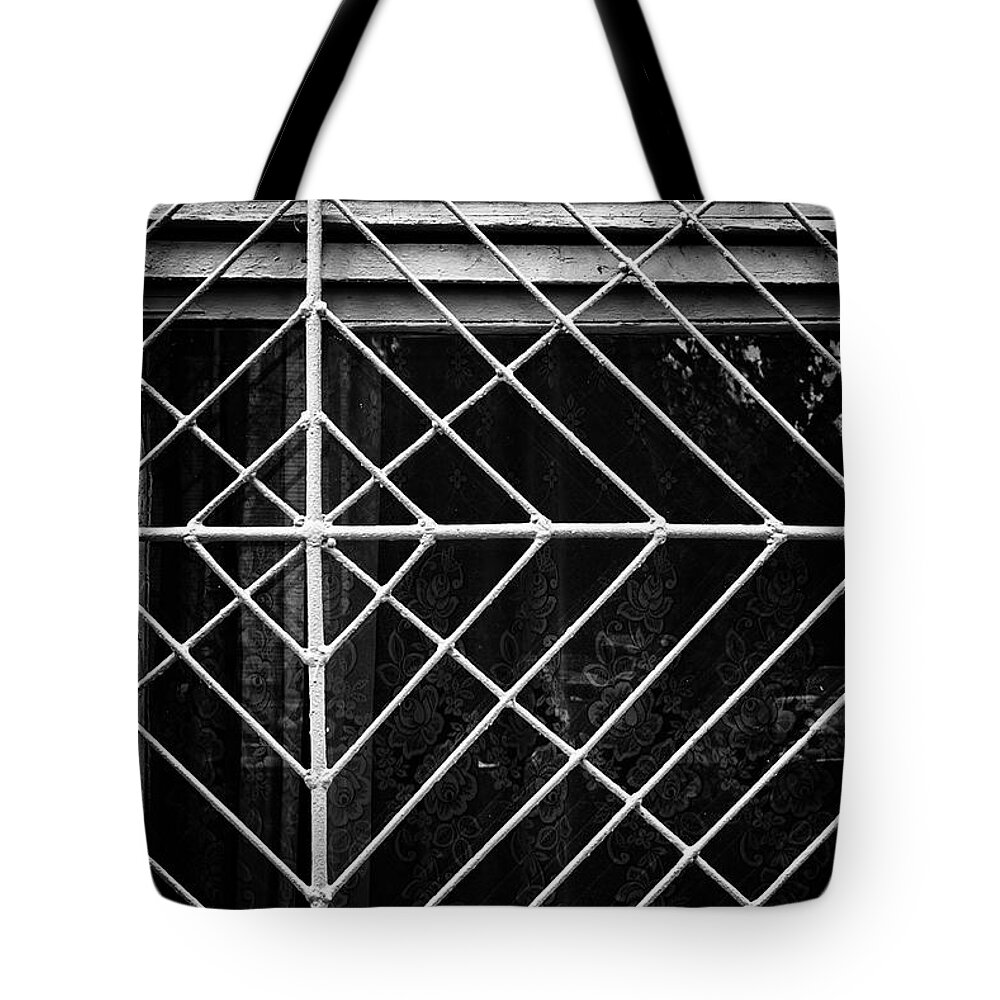 Wall Art Tote Bag featuring the photograph Metal Spider Web Windowframe in Monochrome by John Williams