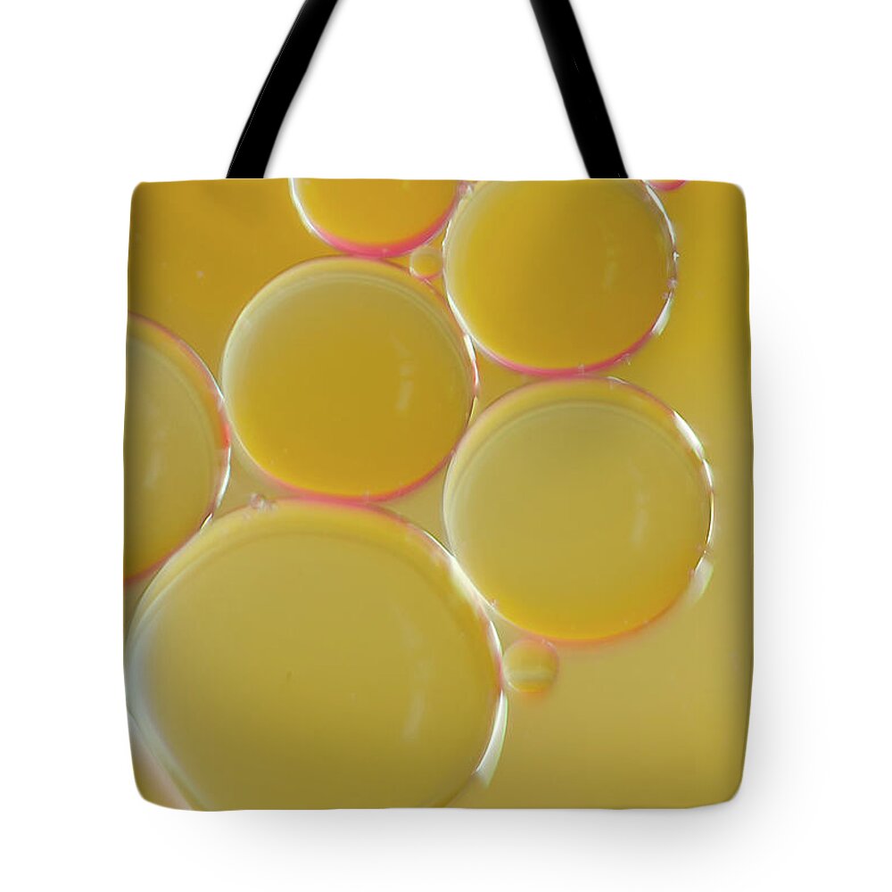 Water Tote Bag featuring the photograph Oil bubbles on water abstract by Andy Myatt