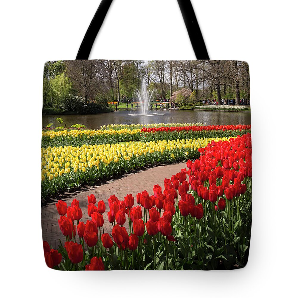 Red Tote Bag featuring the photograph Red and yellow tulips on the river bank in Keukenhof Gardens by Louise Heusinkveld