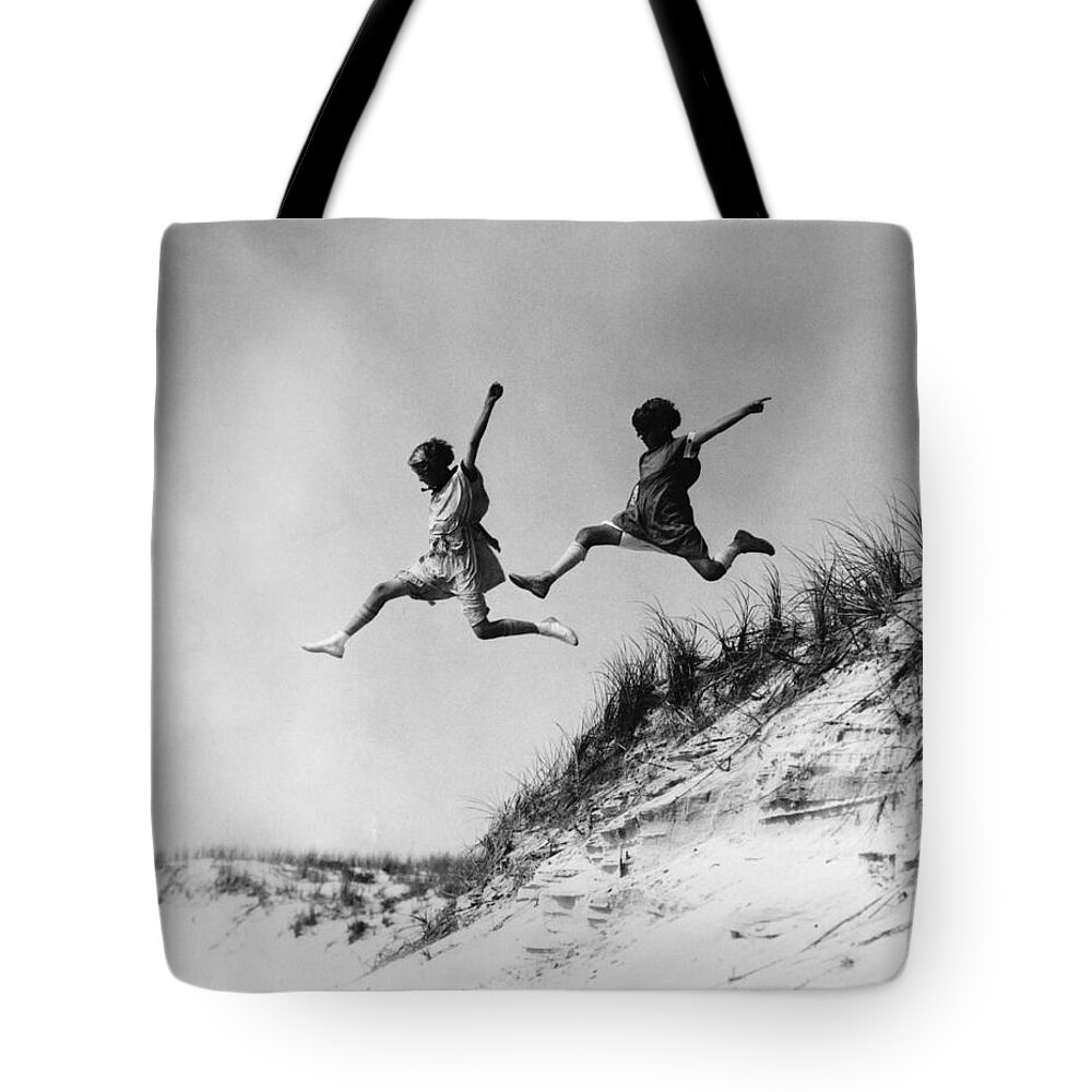1920s Tote Bag featuring the photograph Two Girls Leaping Off Sand Dune by H Armstrong Roberts and ClassicStock