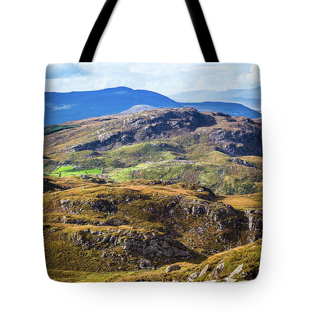 Blue Tote Bag featuring the photograph Undulating green, purple and yellow rocky landscape in Ireland by Semmick Photo