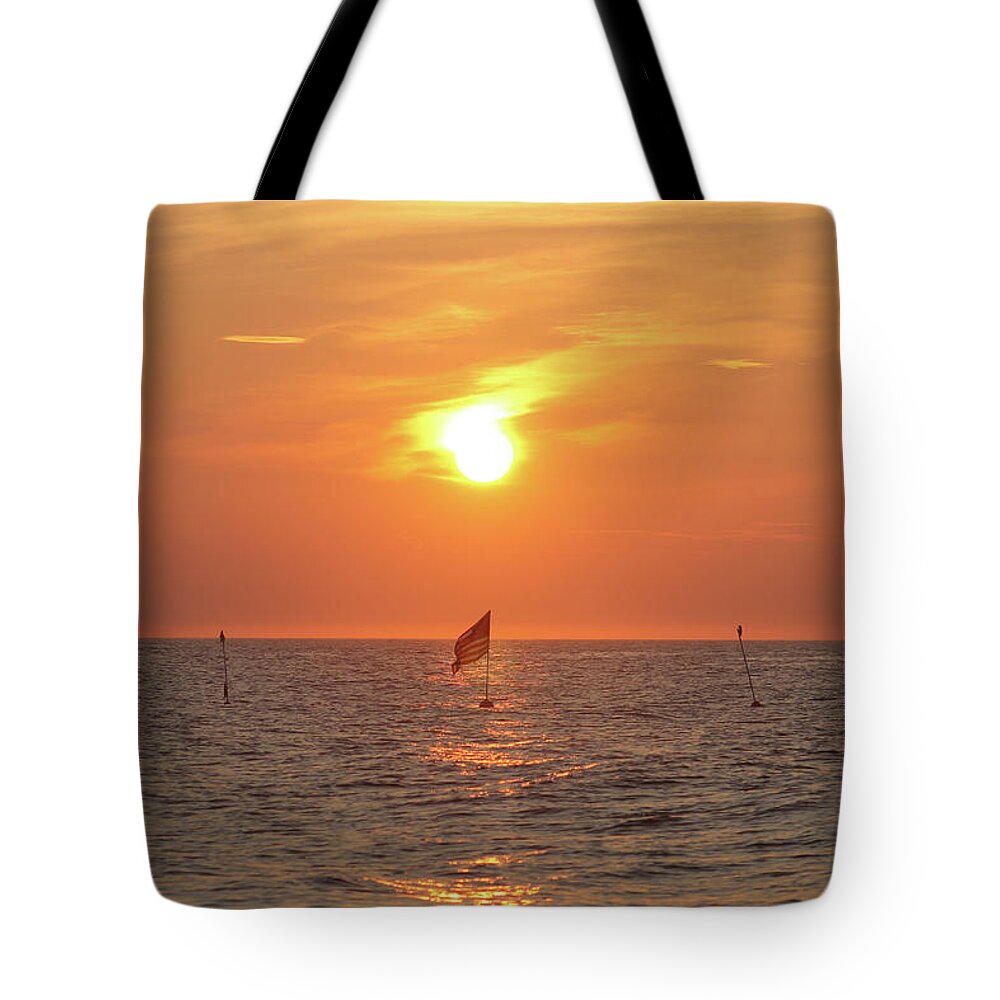 Us Tote Bag featuring the photograph US Flag Floating At Sunrise by Robert Banach