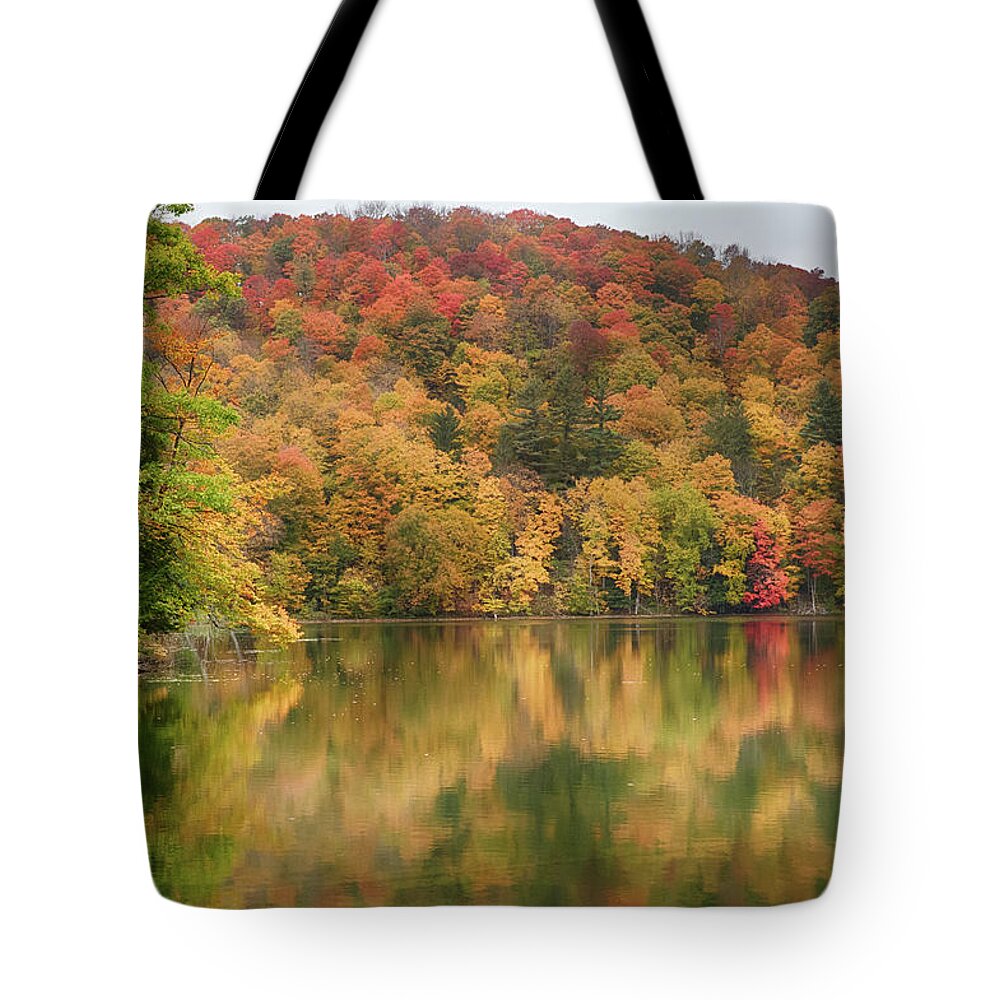 Abenaki Tote Bag featuring the photograph Vermont fall foliage reflected on Pogue Pond by Jeff Folger