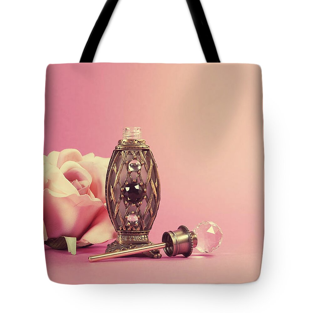Retro Tote Bag featuring the photograph Vintage perfume bottle with crystal stopper and silk rose by Milleflore Images