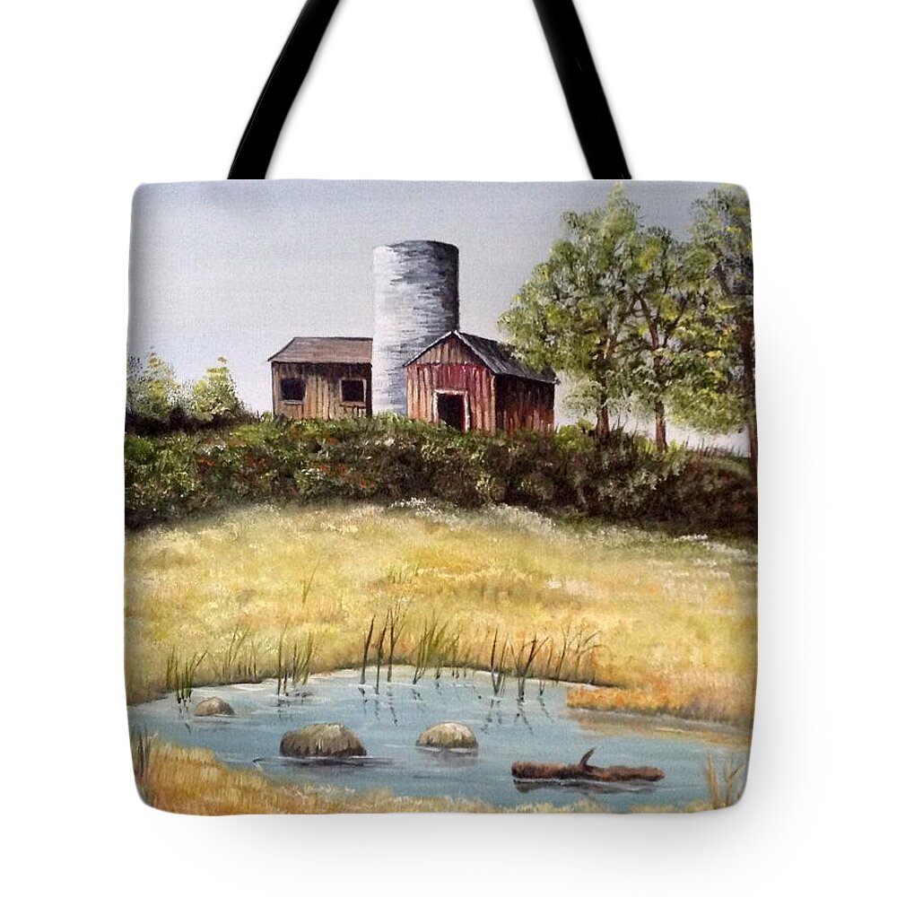 A Set Of Barns Sitting On A Hill With A Concrete Silo. There Are Several Trees Near The Barns And Large Bushes In Front Of The Barns. There Is An Open Meadow And A Small Pond With Rocks And An Old Fence Post In The Foreground. Tote Bag featuring the photograph Windy Meadows by Martin Schmidt