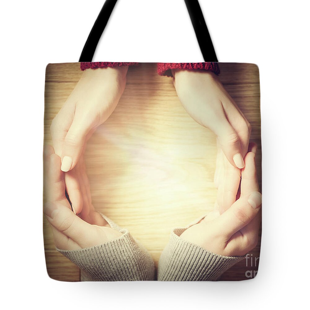 Hands Tote Bag featuring the photograph Woman and man making circle with hands. Warm light inside by Michal Bednarek