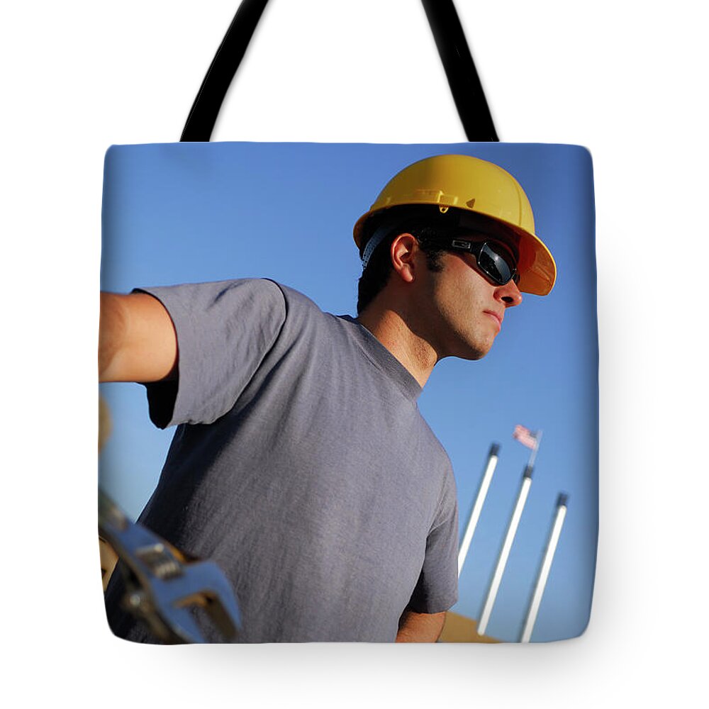 Young Tote Bag featuring the photograph Young male construction worker pausing with wrench by Reimar Gaertner