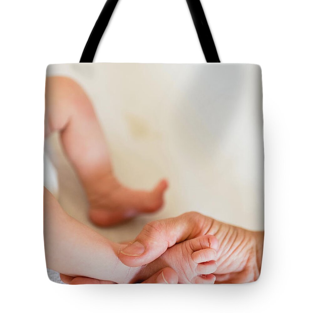 Adult Tote Bag featuring the photograph Mommy grabbing the little feet of her newborn daughter. #1 by Joaquin Corbalan