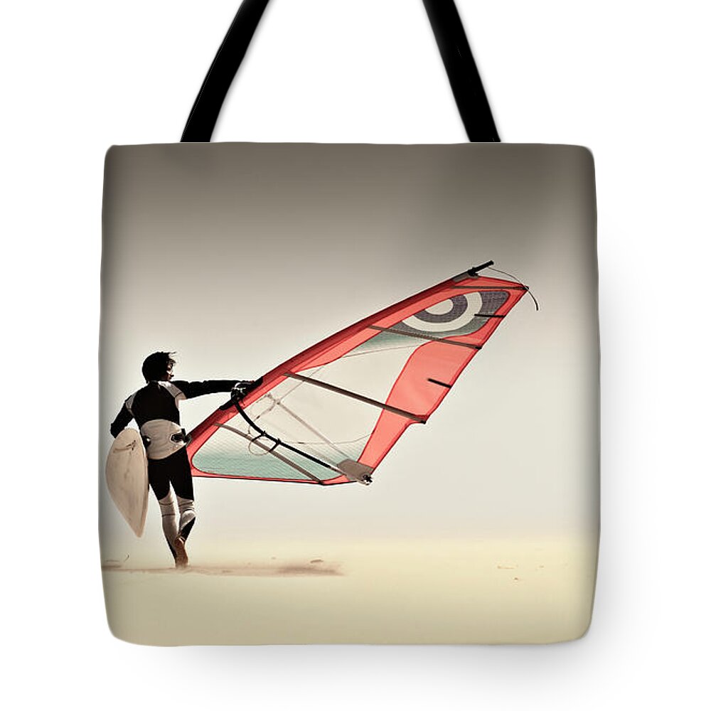 Mature Adult Tote Bag featuring the photograph A Windsurfer Runs On The Sand Of Punta by Ben Welsh / Design Pics