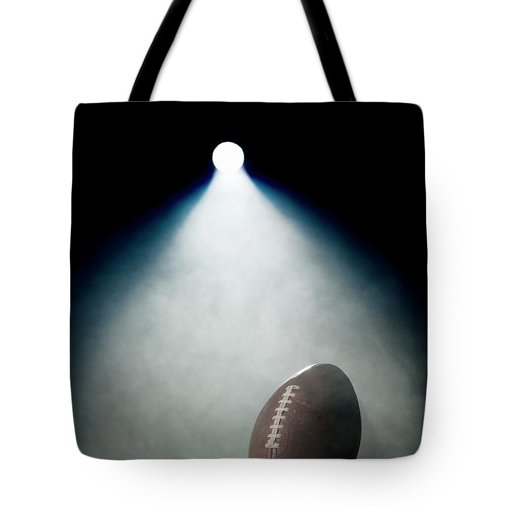 Black Background Tote Bag featuring the photograph American Football In Spotlight by Siri Stafford
