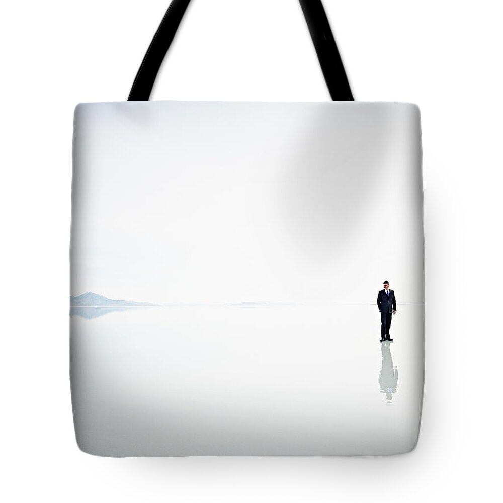 Problems Tote Bag featuring the photograph Businessman Standing Alone On Surface by Thomas Barwick