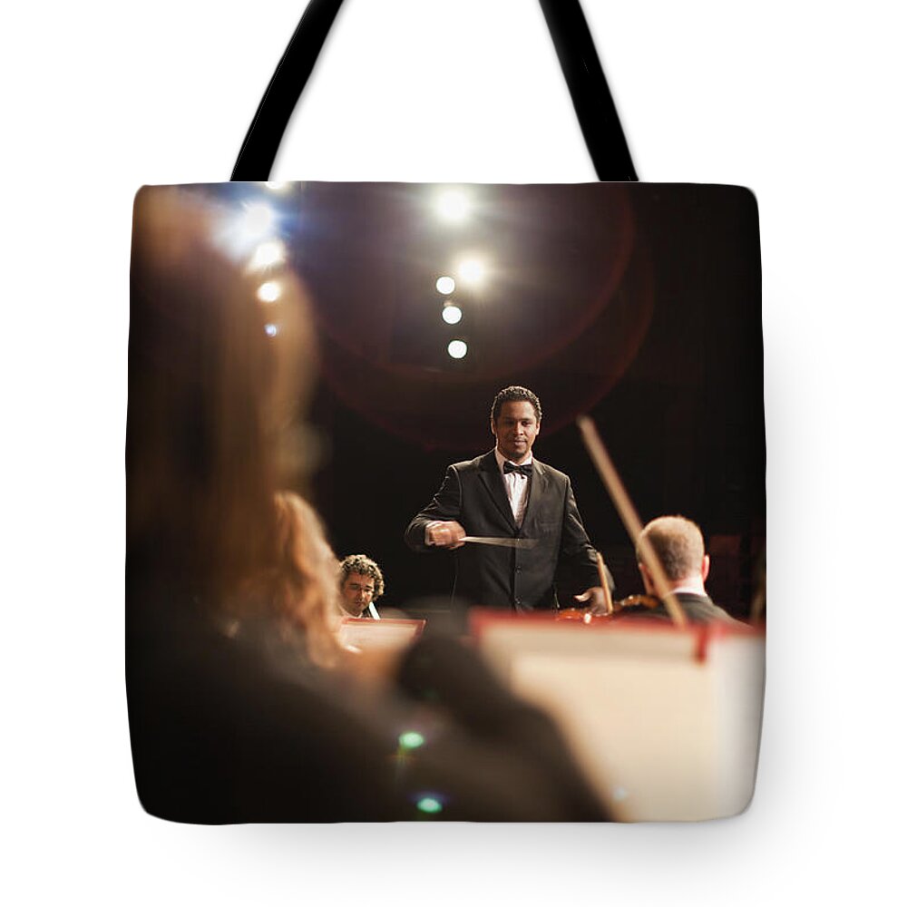 People Tote Bag featuring the photograph Conductor Waving Baton Over Orchestra by Hybrid Images