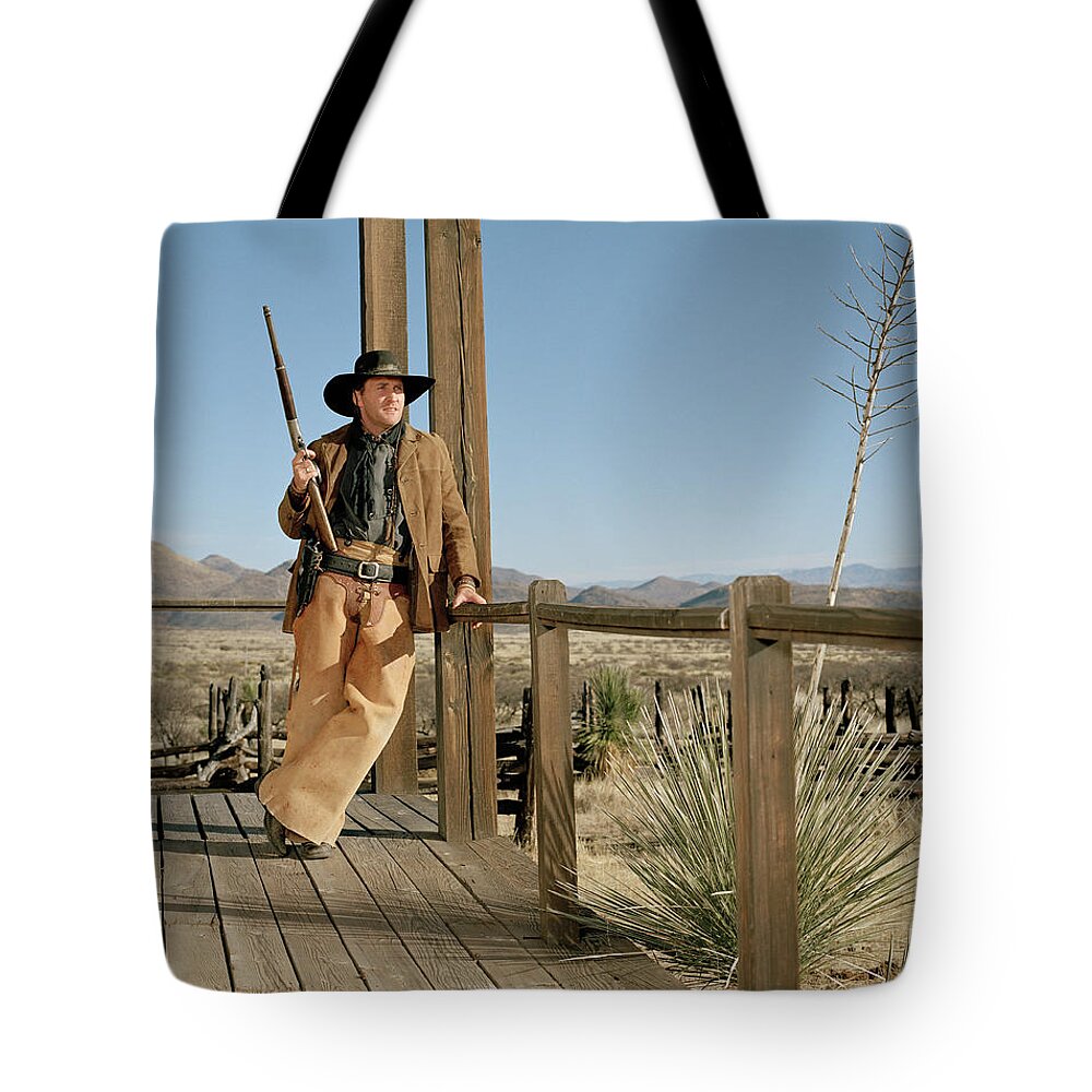 Rifle Tote Bag featuring the photograph Cowboy Standing On Porch by Matthias Clamer