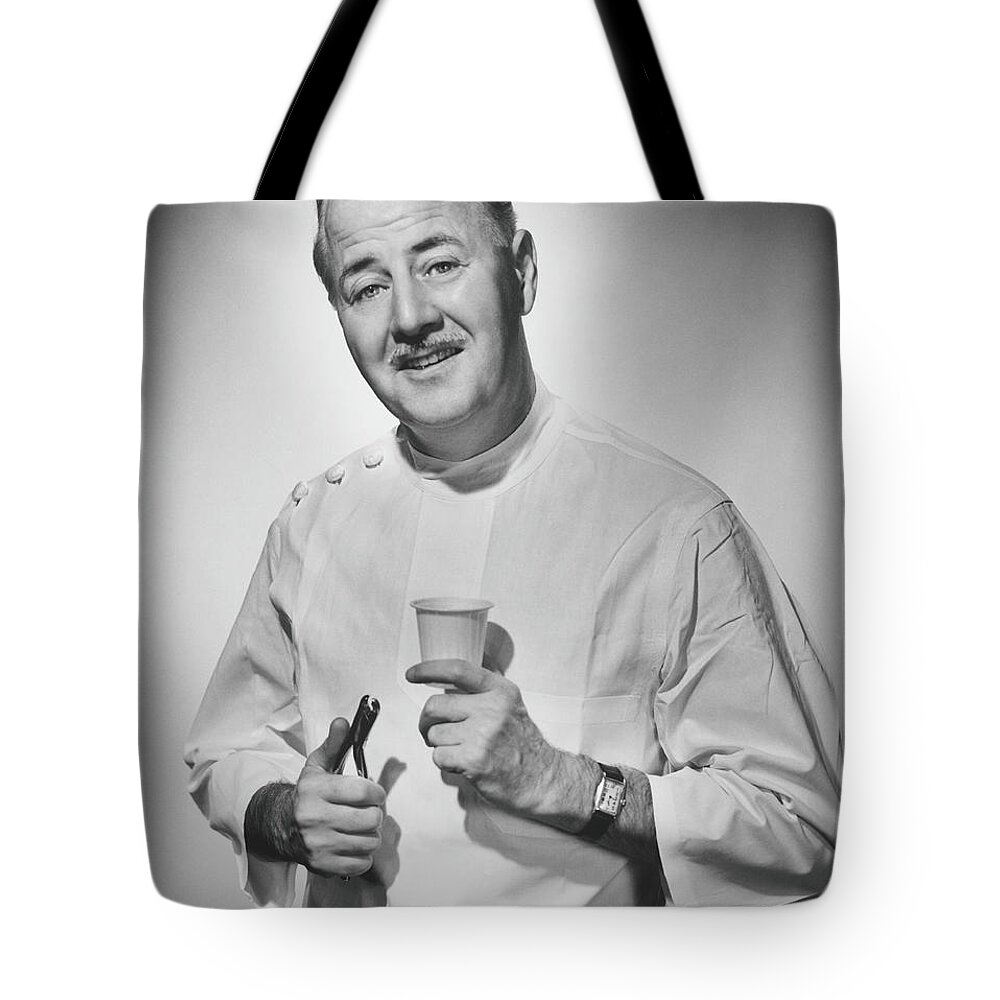 People Tote Bag featuring the photograph Dentist Holding Pliers And Cup Posing by George Marks