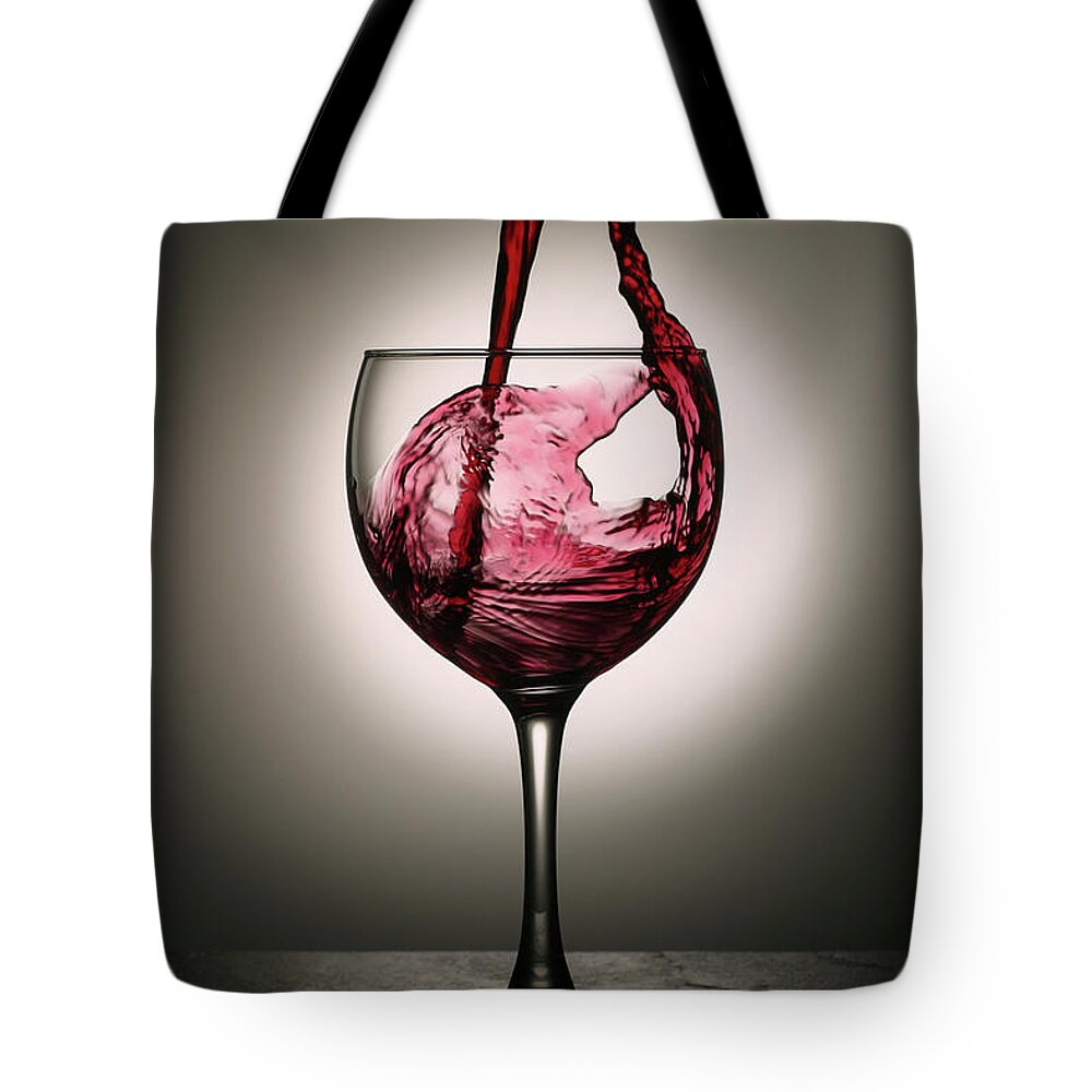 Alcohol Tote Bag featuring the photograph Dramatic Red Wine Splash Into Wine Glass by Donald gruener
