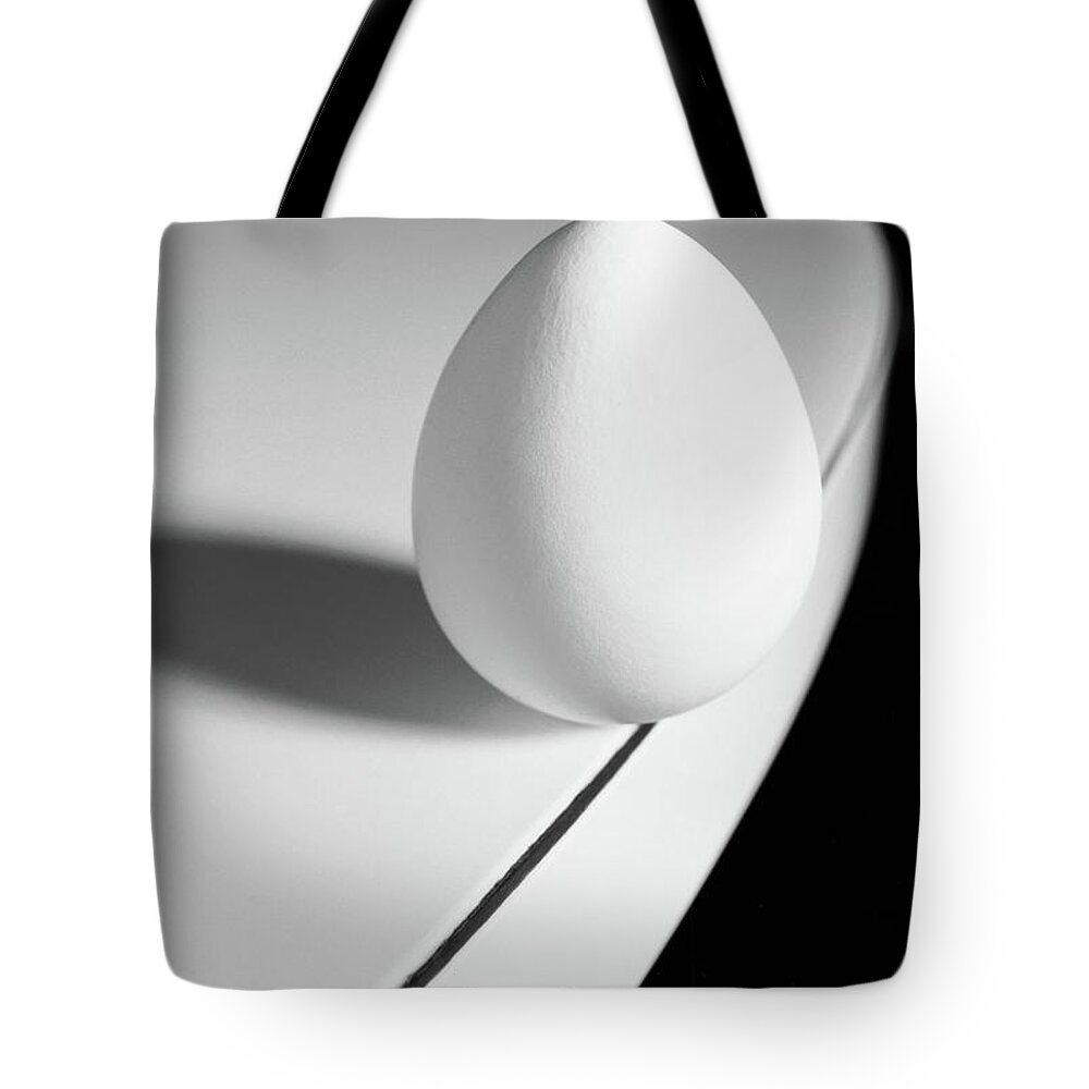 Corporate Business Tote Bag featuring the photograph Egg Carefully Balancing At The Edge Of by Scotspencer