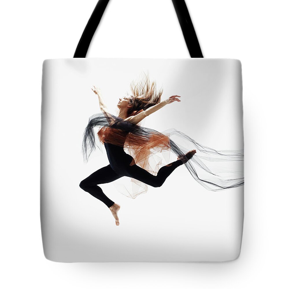 Human Arm Tote Bag featuring the photograph Female Dancer Leaping In Mid Air by Thomas Barwick