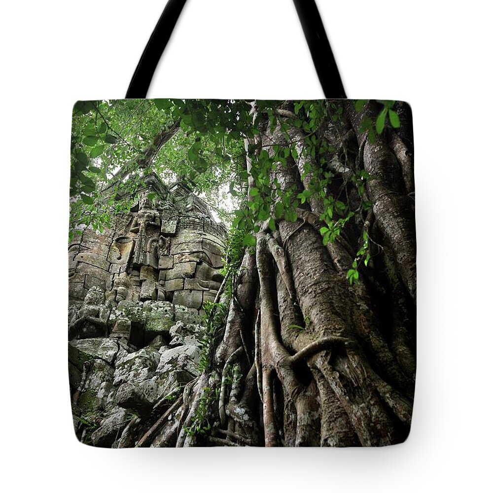 Cambodian Culture Tote Bag featuring the photograph Giant Stone Head In Jungle Ruin At by Timothy Allen