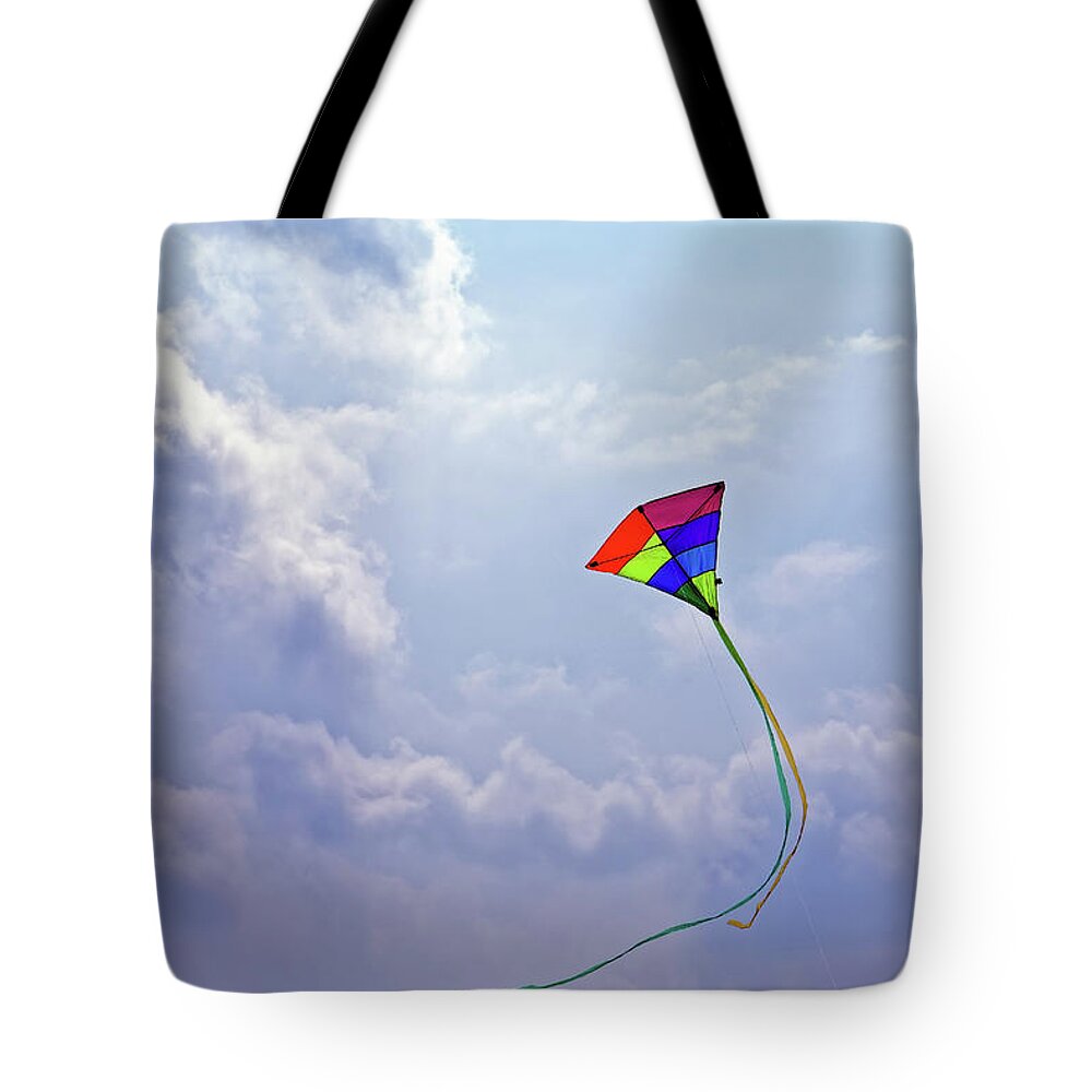 High Flying Swirling Kite Tote Bag featuring the photograph High Flying Multicolored Red Yellow Green Blue Purple Triangular Kite Flying Sunny Cloudy Blue Sky by Robert C Paulson Jr