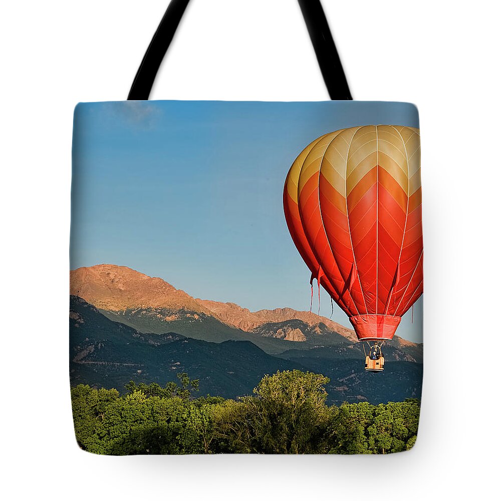 Tranquility Tote Bag featuring the photograph Hot Air Balloon Flies By Pikes Peak by Christopher Coleman