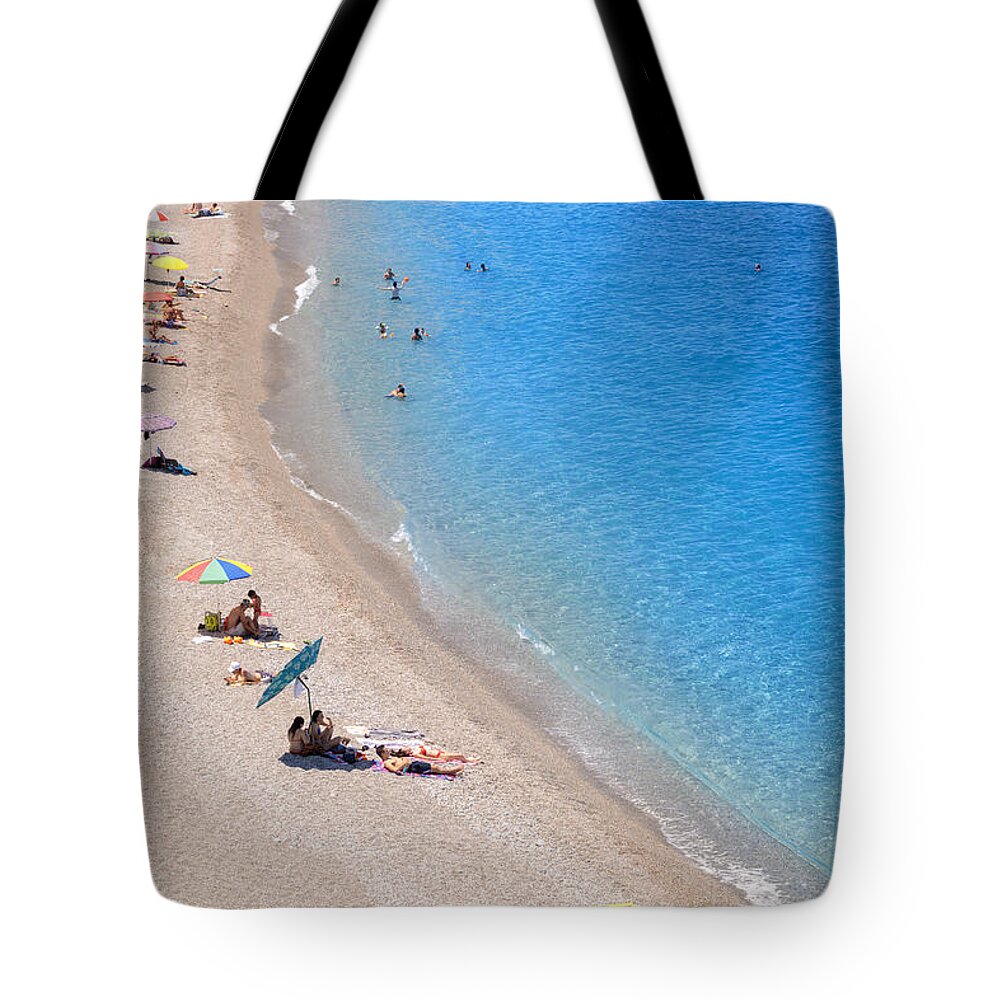 Estock Tote Bag featuring the digital art Italy, Sicily, Messina District, Capo D'orlando, Capo D'orlando. Faro Beach, City Beach With Transparent Sea And Umbrellas. Waterfront With Bathers by Paolo Giocoso