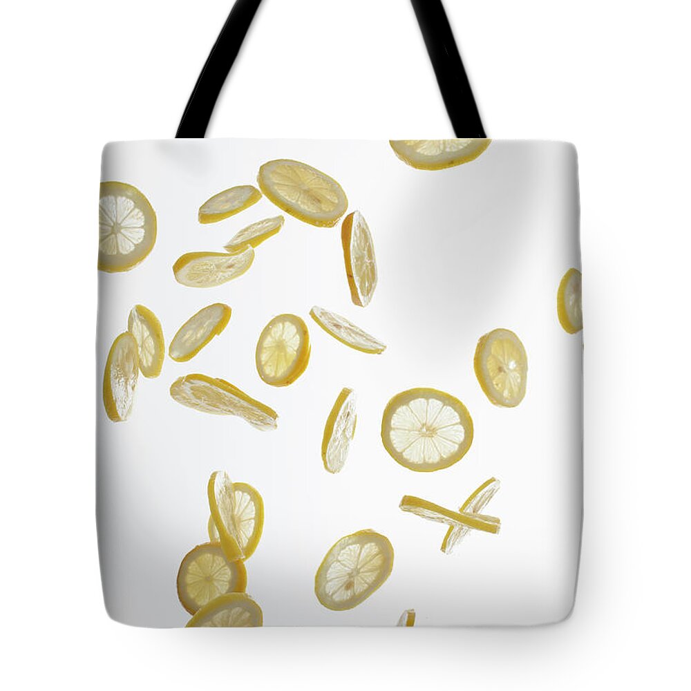 White Background Tote Bag featuring the photograph Lemon Slices Against A White Background by Dual Dual