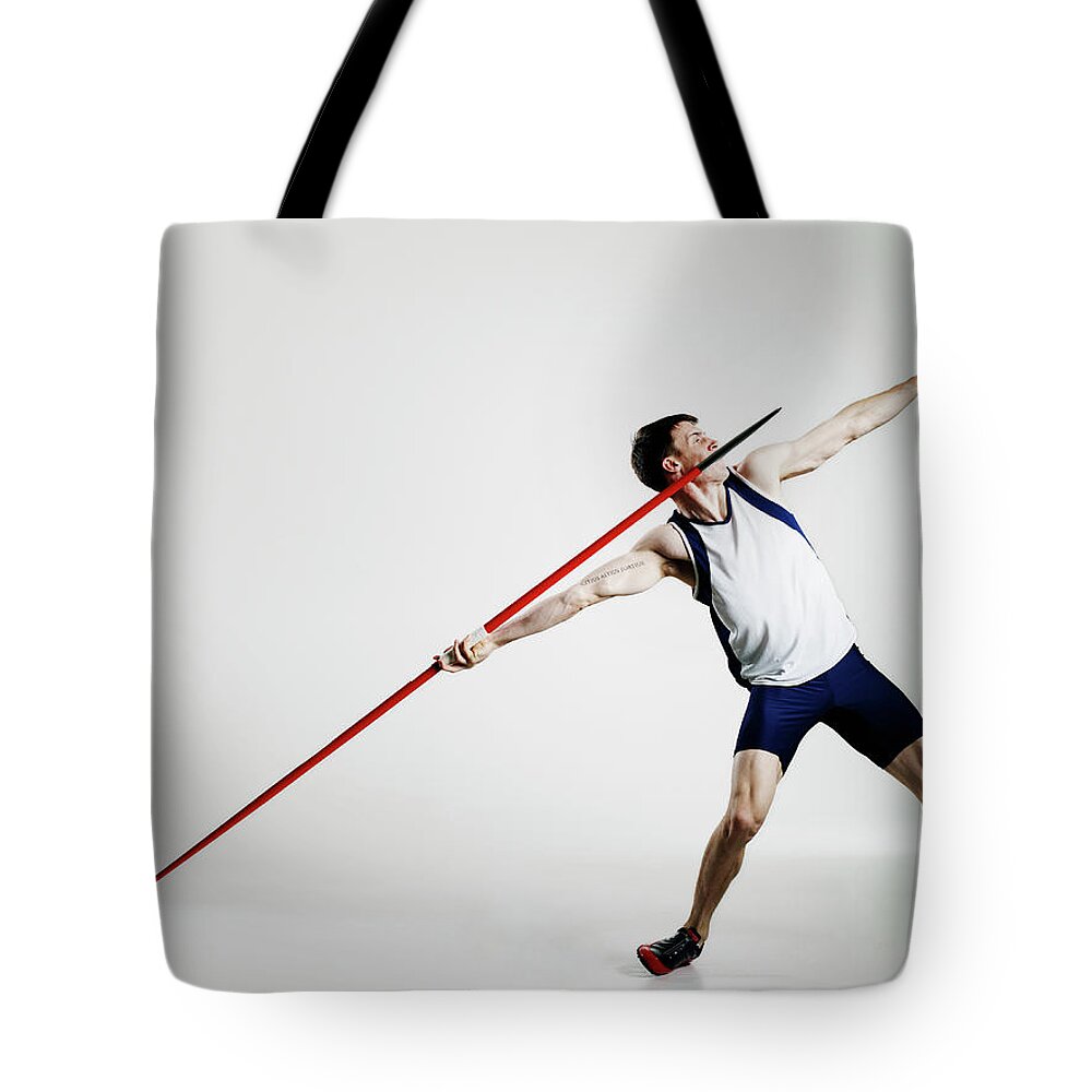 Expertise Tote Bag featuring the photograph Male Track Athlete Preparing To Throw by Thomas Barwick