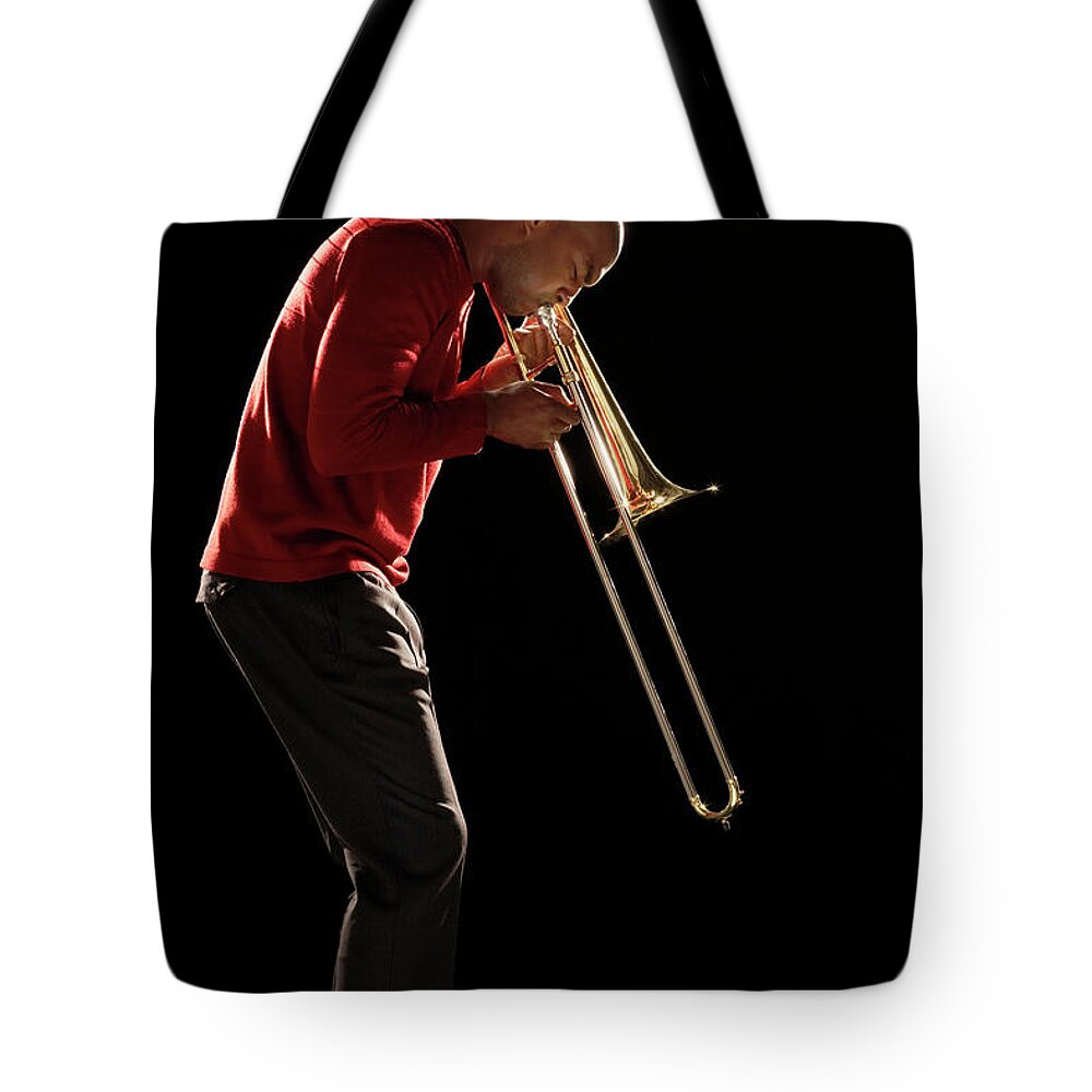 People Tote Bag featuring the photograph Man Playing Trombone, Side View by Moodboard