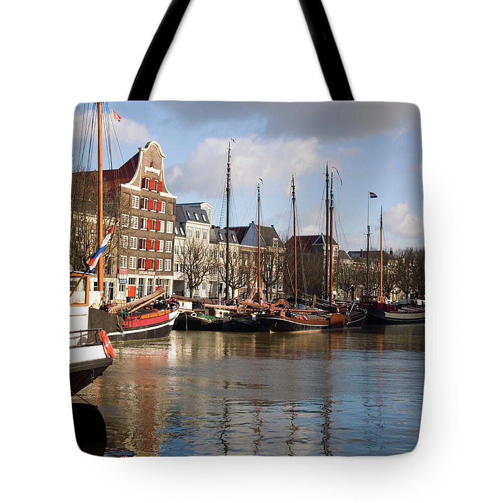 Netherlands Tote Bag featuring the photograph Medieval Harbour With Traditional Ships by Roel Meijer