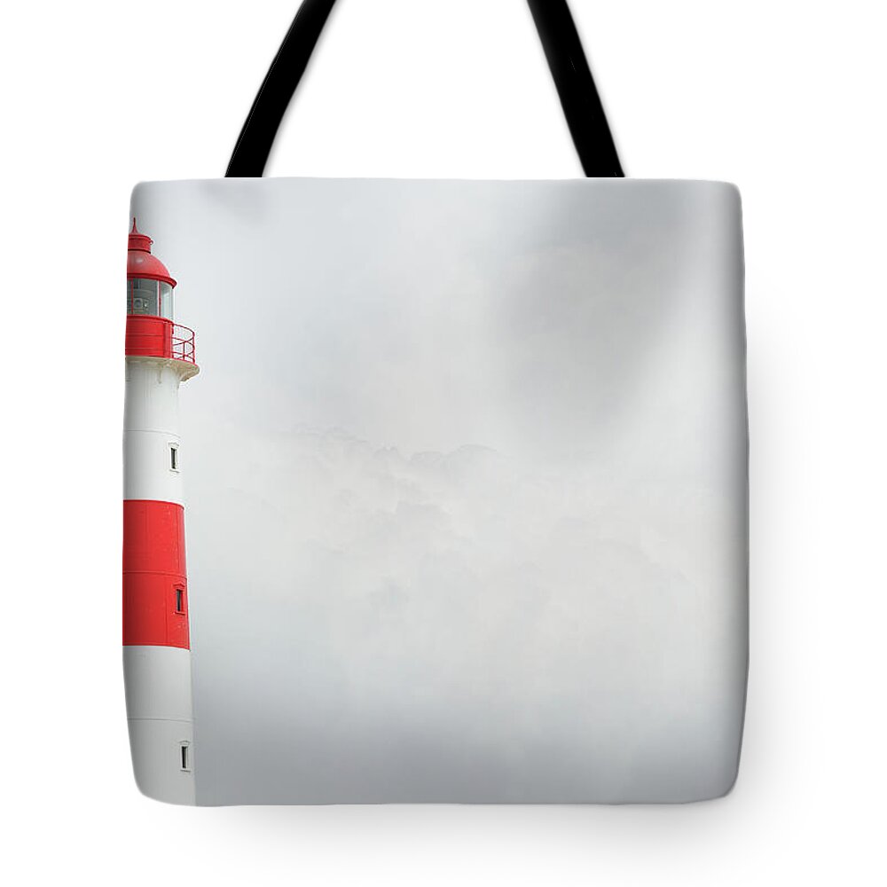Water's Edge Tote Bag featuring the photograph Partly Sunlit Lighthouse, Bad Weather by Olaser