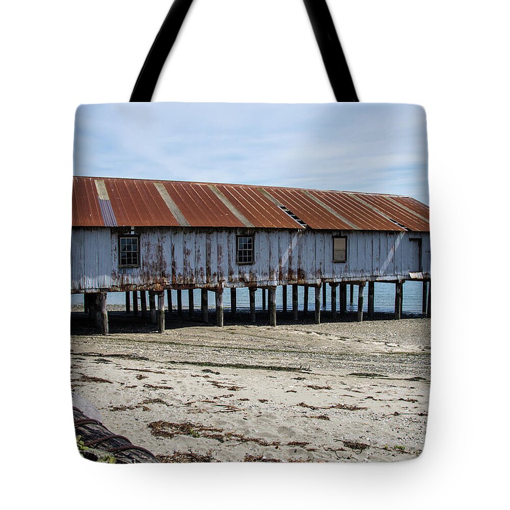 Pilings And Rusty Roof Tote Bag featuring the photograph Pilings and Rusty Roof by Tom Cochran
