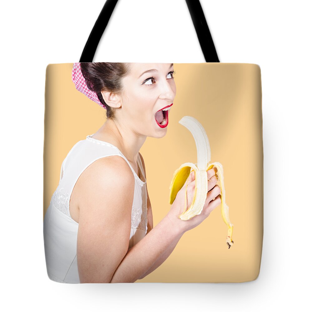 Fruit Tote Bag featuring the photograph Pin-up woman eating fruit on studio background by Jorgo Photography