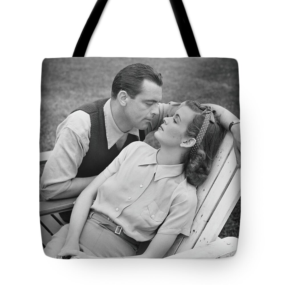 Heterosexual Couple Tote Bag featuring the photograph Romantic Couple Relaxing On Deckchair by George Marks