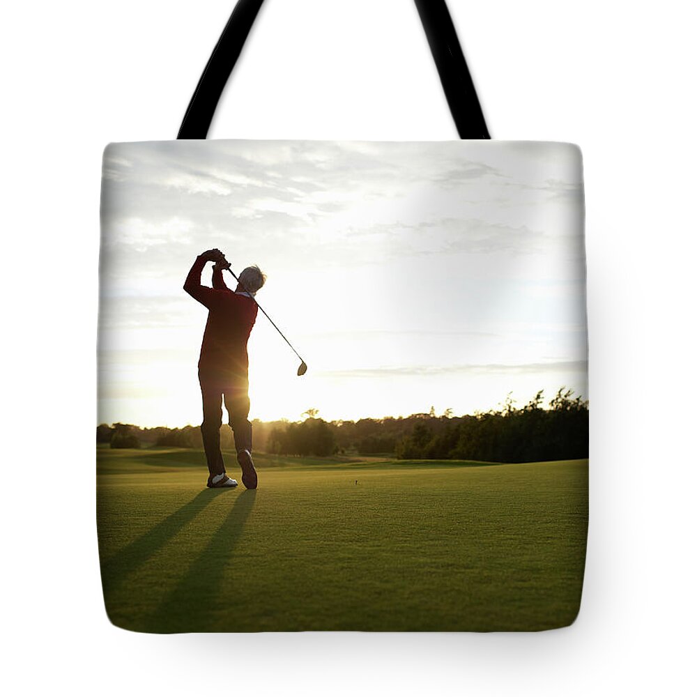 Recreational Pursuit Tote Bag featuring the photograph Senior Golfer Teeing Off On Golf Course by Dougal Waters