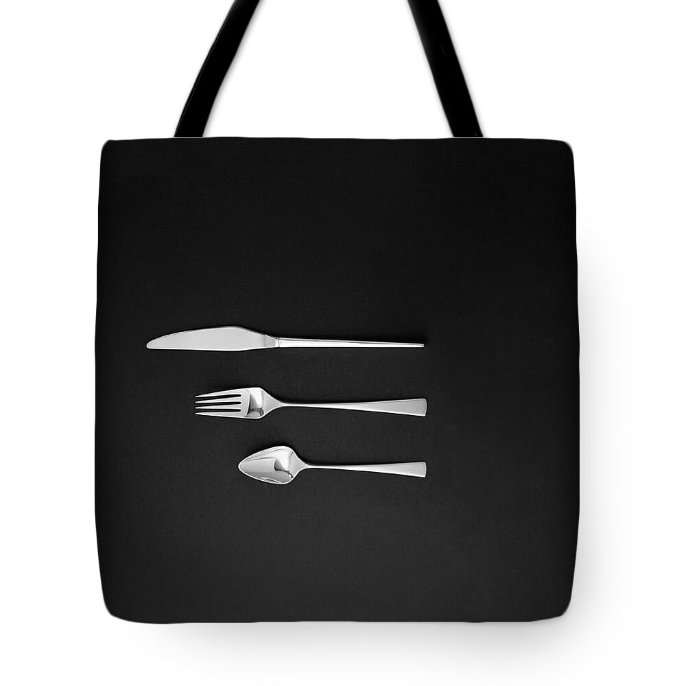 In A Row Tote Bag featuring the photograph Spoon, Fork And Butter Knife On Black by Tom Kelley Archive