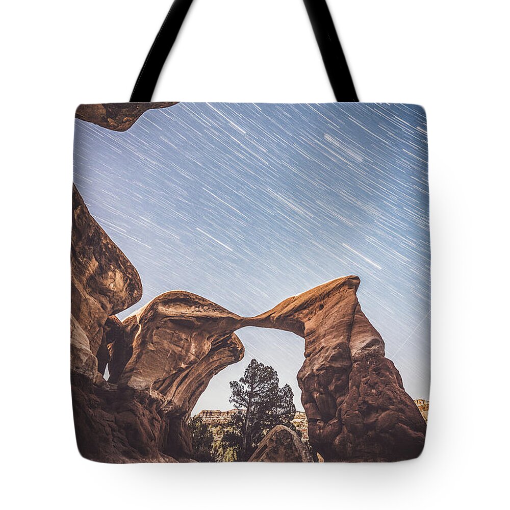 Devil's Garden Tote Bag featuring the photograph Star trails over Metate Arch by Mati Krimerman