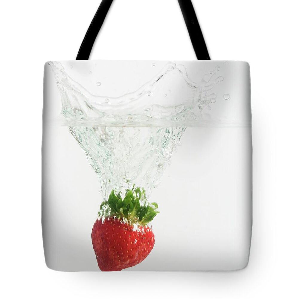 White Background Tote Bag featuring the photograph Strawberry Dropped Into Water by Tetra Images
