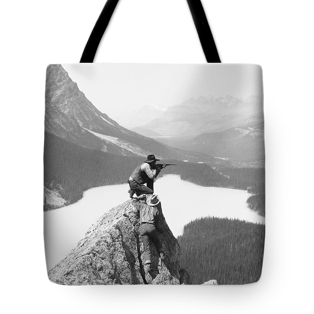 Rifle Tote Bag featuring the photograph Two Cowboys On Top Of Rocky Crag, One by H. Armstrong Roberts