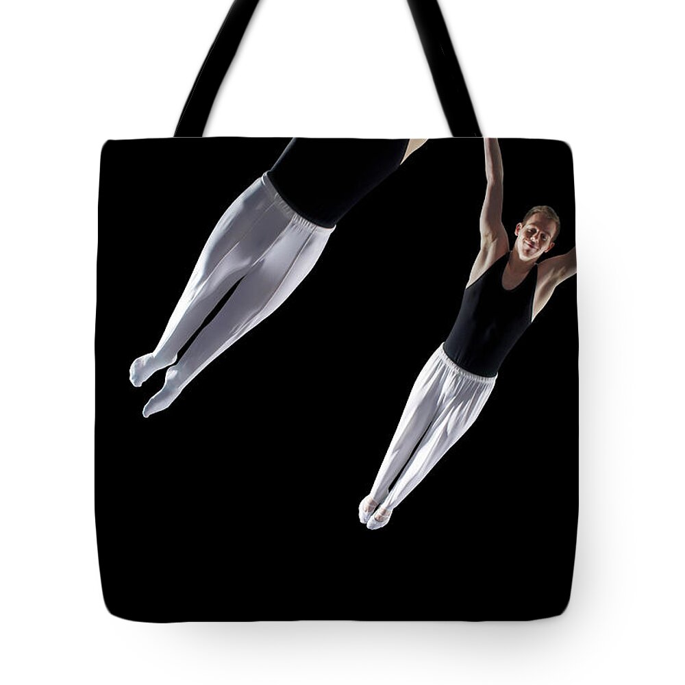 Human Arm Tote Bag featuring the photograph Two Male Trampolinists Mid Flight by Peter Muller