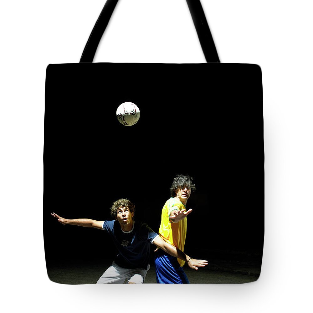 Young Men Tote Bag featuring the photograph Two Soccer Players Heading Ball, Night by Hans Neleman