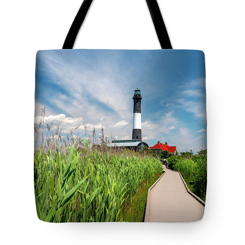 Estock Tote Bag featuring the digital art Usa, New York, Long Island, Wooden Path To The Fire Island Lighthouse Surrounded By Beach Grass, Blue Sky, White Clouds. by Alejandra Uribe Posada