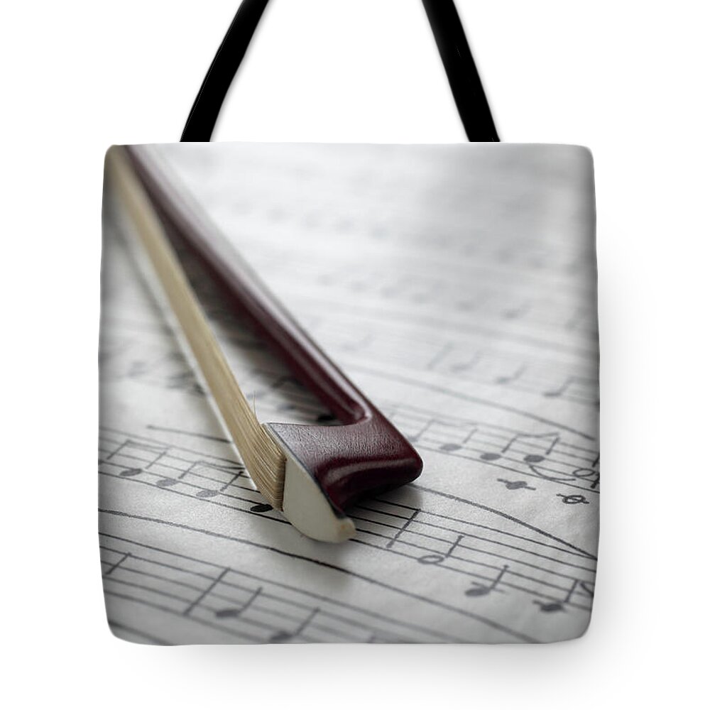 Sheet Music Tote Bag featuring the photograph Violin Bow On Music Sheet by Daniel Allan